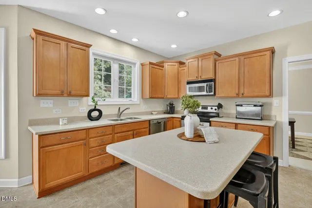 a kitchen with stainless steel appliances granite countertop a stove top oven a sink a refrigerator and white cabinets with wooden floor