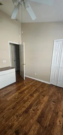 an empty room with wooden floor a ceiling fan and window