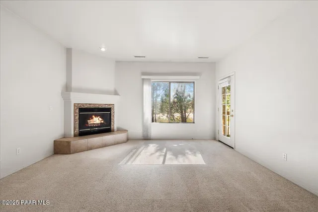 an empty room with windows and fireplace