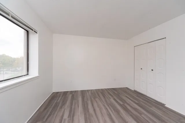 a view of a room that has wooden floor and a window