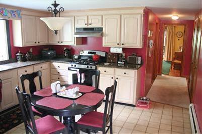 157 Poponessett Road Cotuit, MA 02635 - Photo 19 of 25 a kitchen with stainless steel appliances kitchen island granite countertop a dining table chairs and a refrigerator