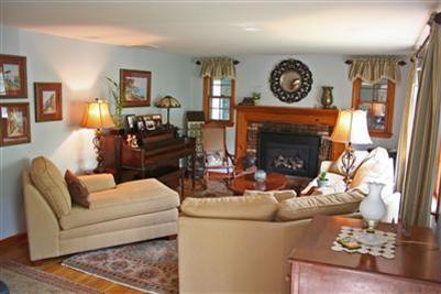 157 Poponessett Road Cotuit, MA 02635 - Photo 2 of 25 a living room with furniture a clock and a fireplace