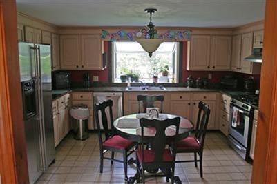 157 Poponessett Road Cotuit, MA 02635 - Photo 4 of 25 a kitchen with a table chairs refrigerator and microwave
