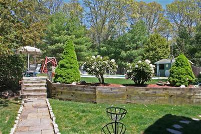 157 Poponessett Road Cotuit, MA 02635 - Photo 8 of 25 a view of a garden with a bench