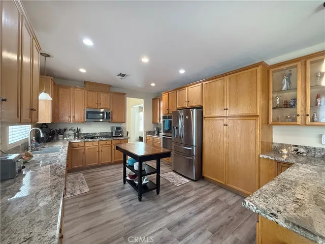 a kitchen with stainless steel appliances kitchen island granite countertop a refrigerator and a stove top oven