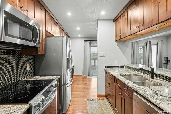 a kitchen with granite countertop stainless steel appliances and wooden cabinets