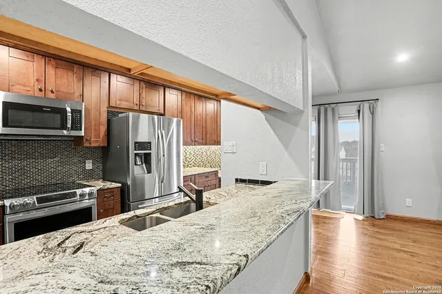 a kitchen with stainless steel appliances granite countertop a stove refrigerator and microwave