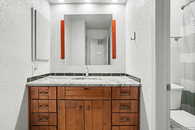 a bathroom with a granite countertop sink and a mirror