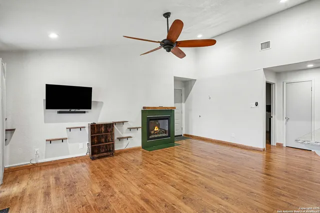 a view of a livingroom with a fireplace a ceiling fan and windows