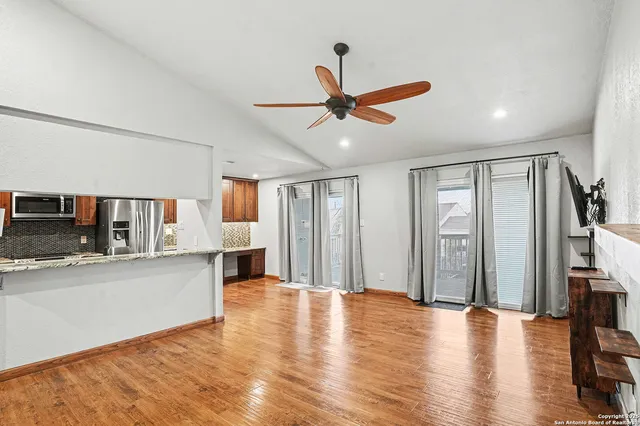 a view of a living room with wooden floor and a ceiling fan