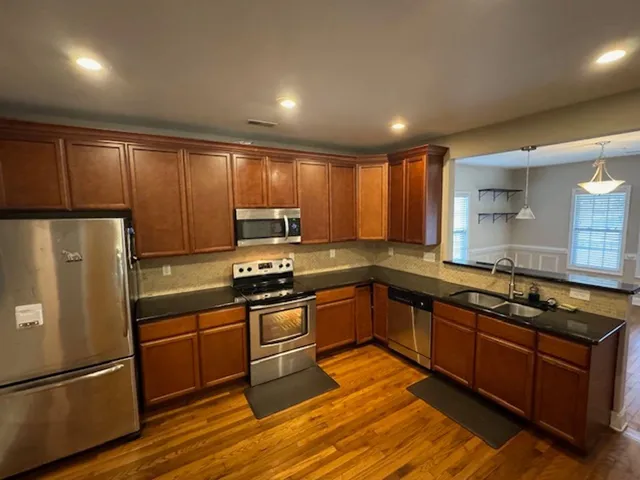 a kitchen with stainless steel appliances granite countertop a refrigerator a sink dishwasher a stove and a refrigerator
