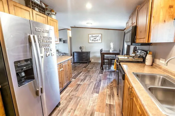 a kitchen with stainless steel appliances granite countertop a refrigerator a sink dishwasher a stove and white countertops with wooden floor