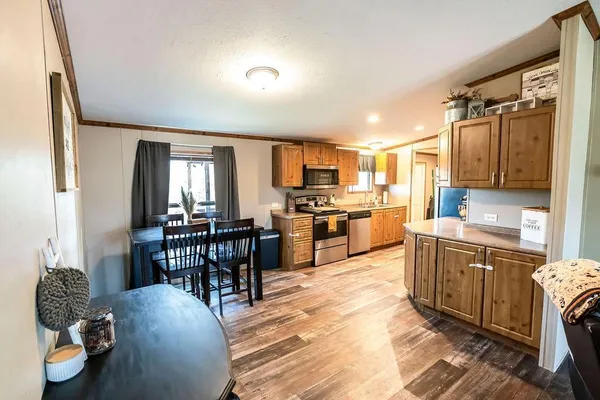 a kitchen with stainless steel appliances kitchen island granite countertop a table chairs in it and a window