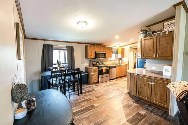 a kitchen with stainless steel appliances kitchen island granite countertop a table chairs in it and a window