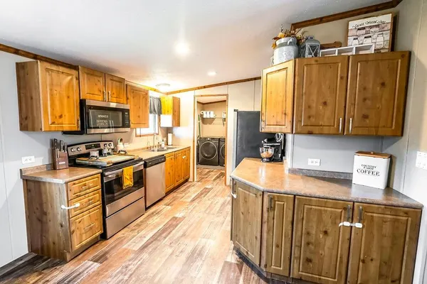 a kitchen with stainless steel appliances granite countertop a stove a sink dishwasher a microwave oven and a refrigerator with wooden floor