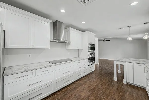 a kitchen with granite countertop white cabinets and stainless steel appliances