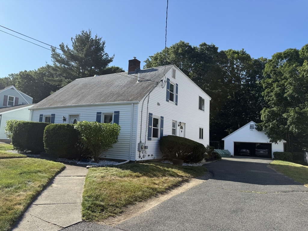 a front view of house with yard and trees in the background