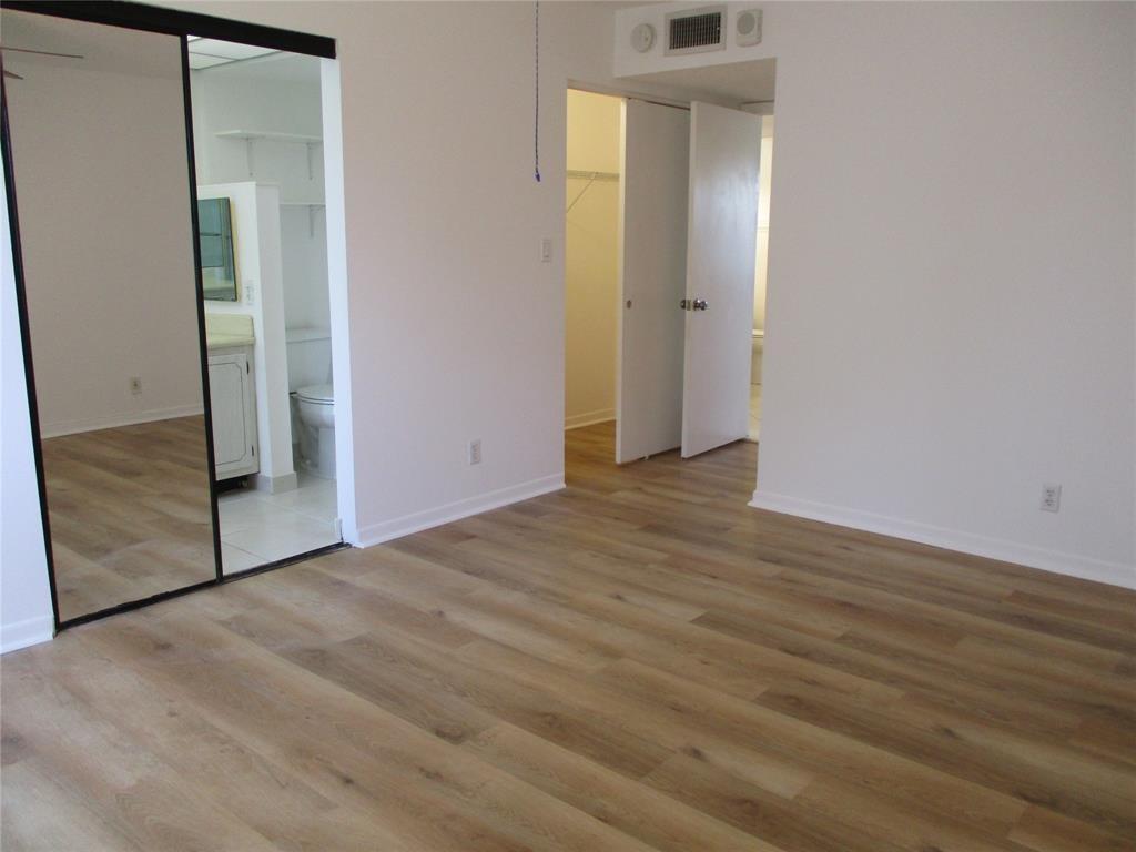 9233 Southwest 8th Street, Unit 311 Boca Raton, FL 33428 - Photo 13 of 19 an empty room with wooden floor and mirror