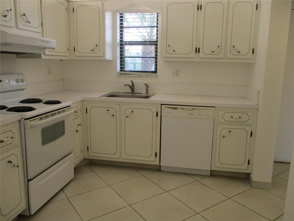 9233 Southwest 8th Street, Unit 311 Boca Raton, FL 33428 - Photo 5 of 19 a kitchen with white cabinets and white appliances