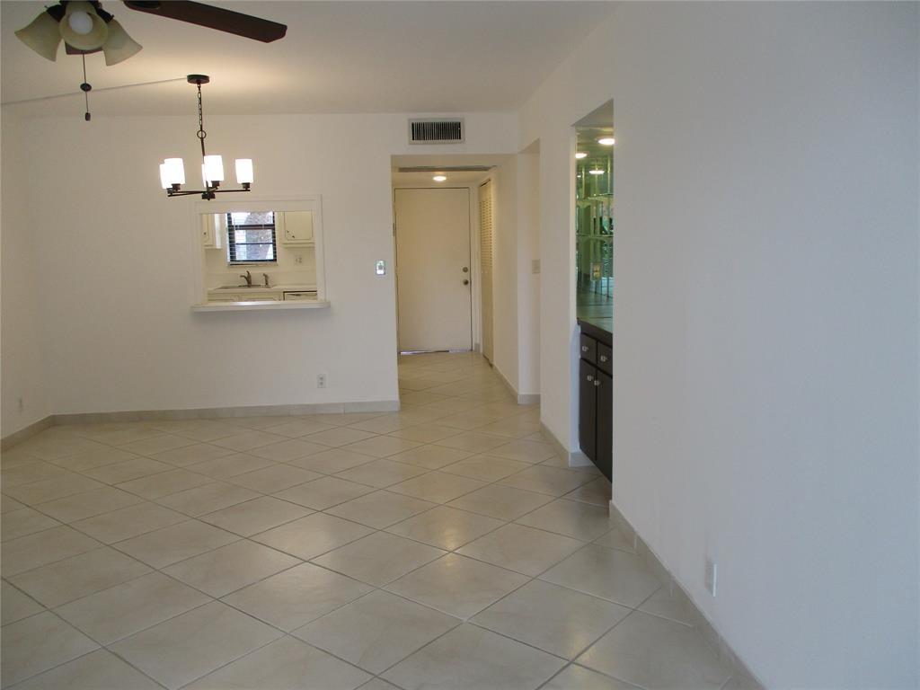 9233 Southwest 8th Street, Unit 311 Boca Raton, FL 33428 - Photo 7 of 19 en empty room with chandelier fan and kitchen view