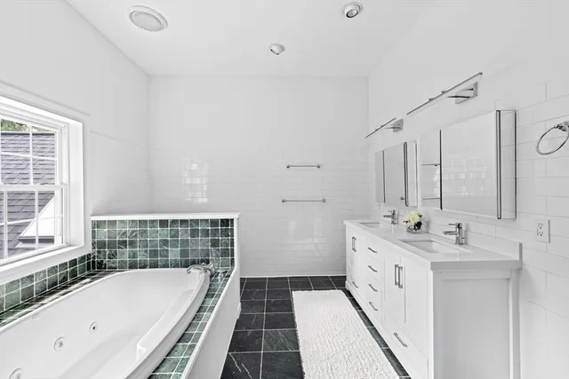 a bathroom with a double vanity sink mirror and bathtub