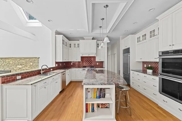 a large white kitchen with a large window a sink and stainless steel appliances
