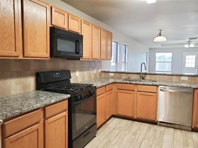 a kitchen with granite countertop cabinets stainless steel appliances a sink and a window