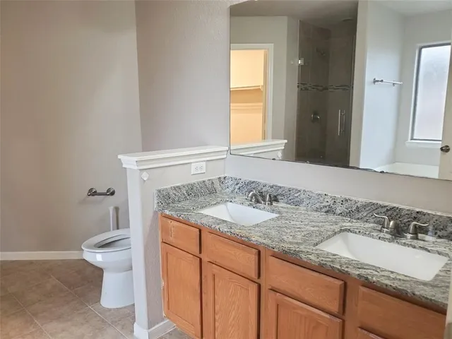 a bathroom with a granite countertop sink and a toilet