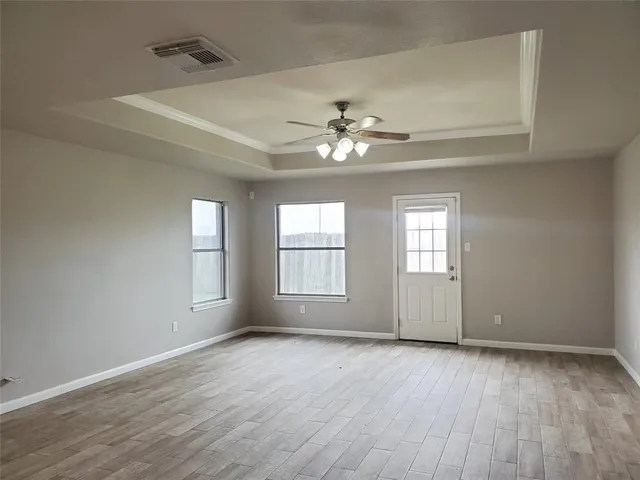 a view of empty room with wooden floor and fan