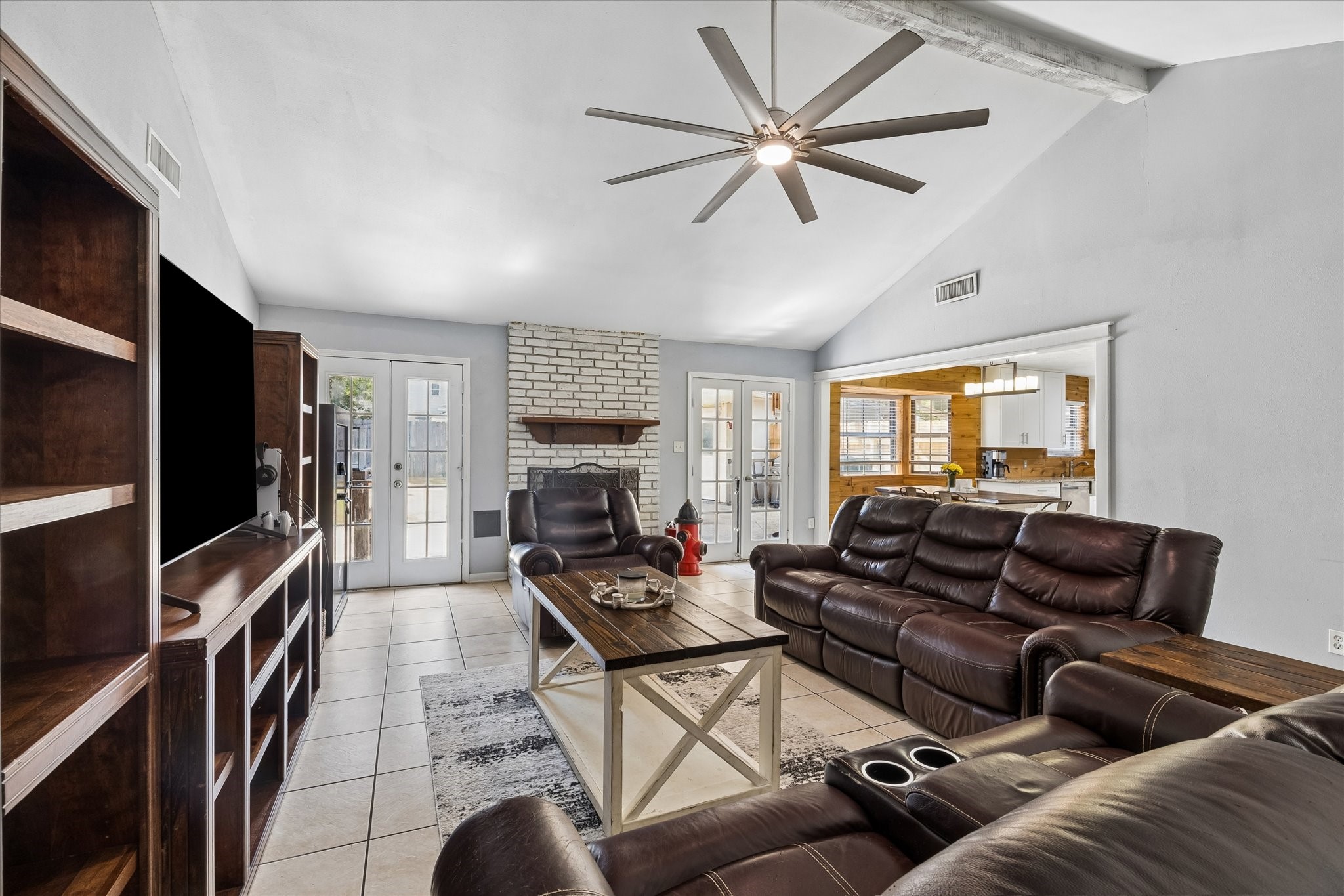 23115 Stepinwolf Lane Spring, TX 77373 - Photo 3 of 18 Spacious living room with vaulted ceiling, featuring a cozy brick fireplace and ample natural light from large windows.