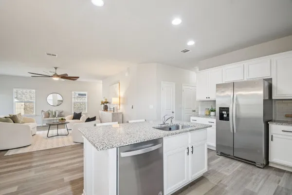 a kitchen with stainless steel appliances kitchen island granite countertop a refrigerator a sink dishwasher a stove and a dining table with wooden floor