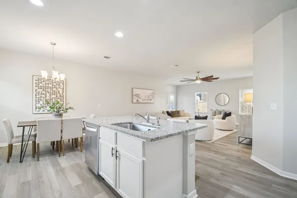 a open kitchen with a sink dishwasher a dining table and chairs with wooden floor