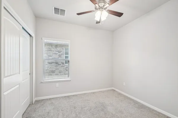 an empty room with a chandelier fan and windows