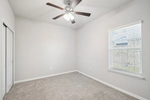 an empty room with a window and a fan