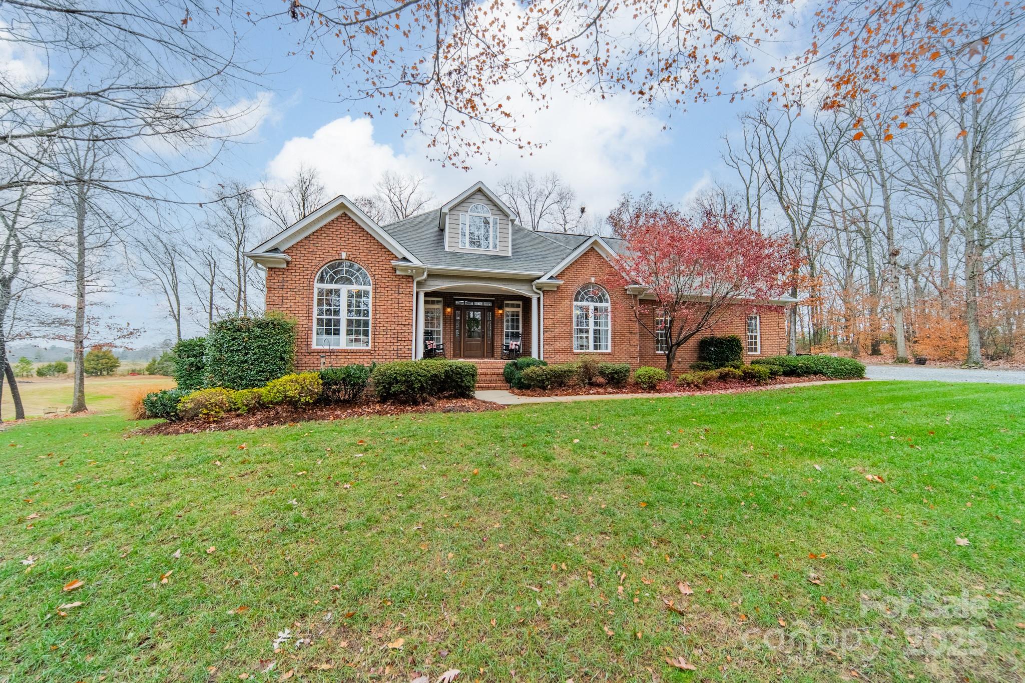 a front view of a house with a garden and trees