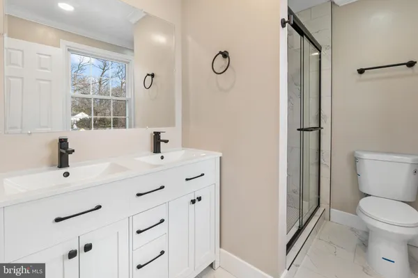 a bathroom with a sink a toilet a mirror and a window