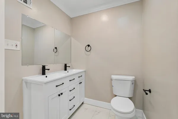 a bathroom with a toilet a sink a mirror and vanity