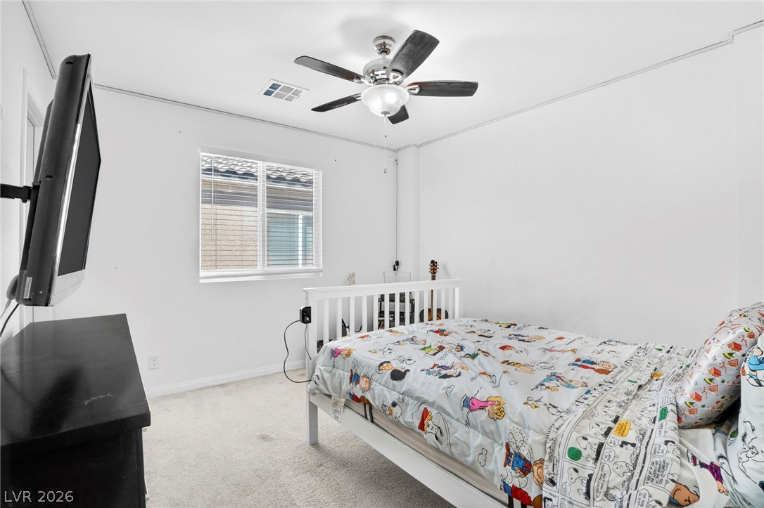 6281 Angora Peak Lane Las Vegas, NV 89115 - Photo 26 of 34 A well-lit bedroom provides comfortable living with soft carpeting and a functional ceiling fan.