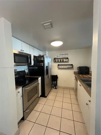 a kitchen with granite countertop a refrigerator and a stove top oven