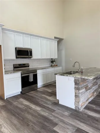 a kitchen with granite countertop a stove top oven and cabinets