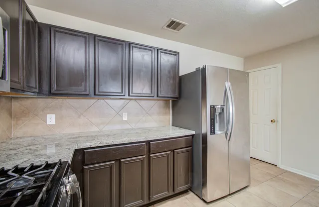 a kitchen with stainless steel appliances granite countertop a refrigerator and a stove top oven