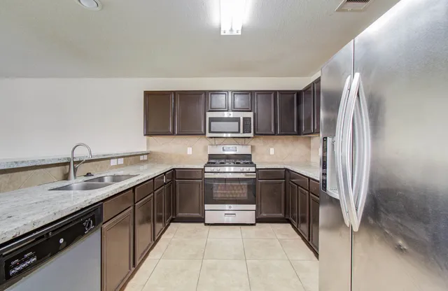 a kitchen with stainless steel appliances granite countertop a sink stove and refrigerator