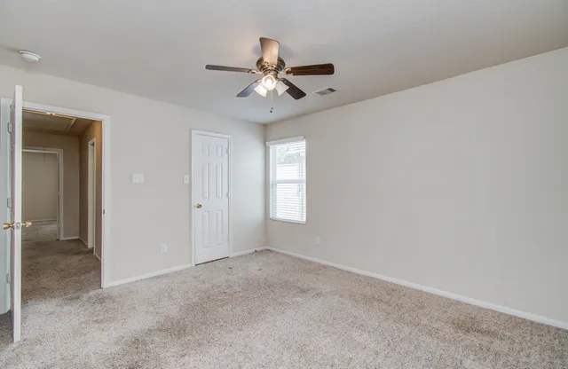 an empty room with windows and chandelier fan