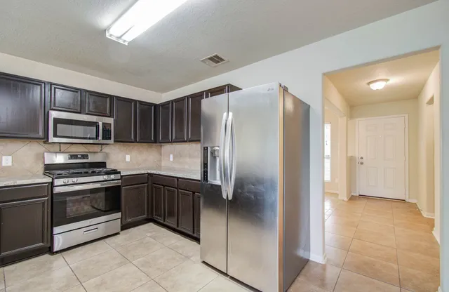 a kitchen with stainless steel appliances granite countertop a refrigerator and a sink