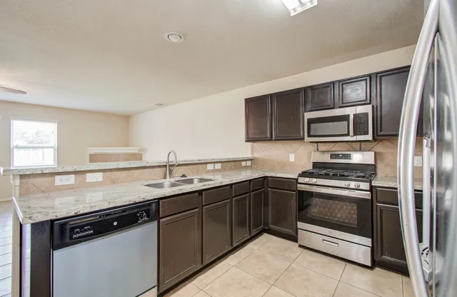 a kitchen with stainless steel appliances granite countertop a sink stove and microwave