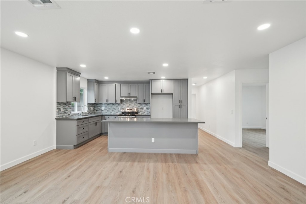 4664 Sierra Street Riverside, CA 92504 - Photo 5 of 30 a open kitchen with kitchen island a sink dishwasher a stove and a refrigerator with wooden floor