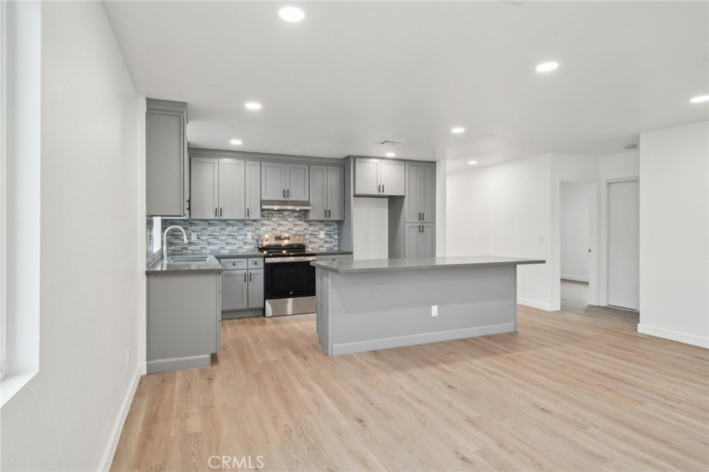 4664 Sierra Street Riverside, CA 92504 - Photo 6 of 30 a kitchen with kitchen island granite countertop wooden floors white cabinets and stainless steel appliances