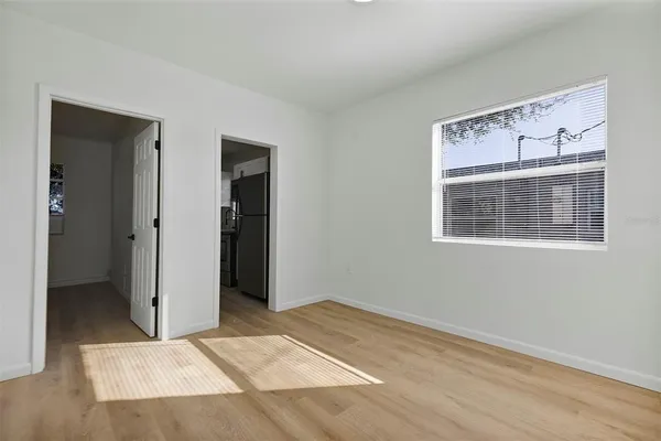 a view of an empty room with wooden floor and a window
