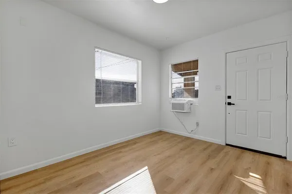 a view of an empty room with wooden floor and a window