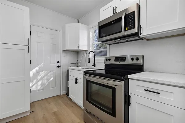 a kitchen with stainless steel appliances white cabinets and a stove a microwave oven